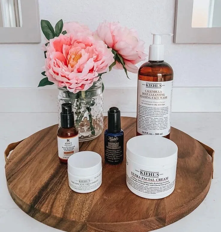 Kiehl's facial products with peonies on a wooden board
