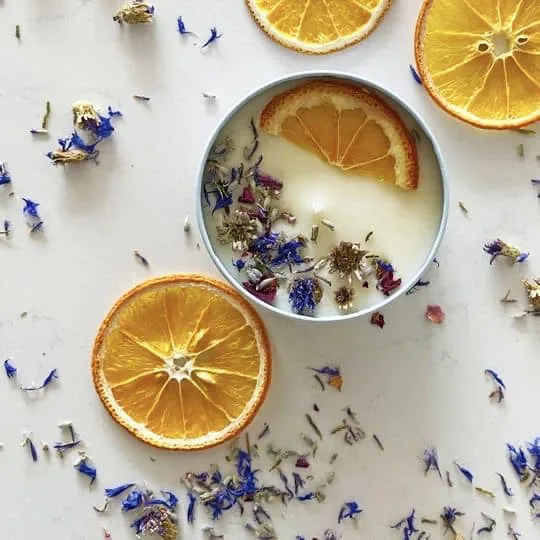 Botanical candle in a tin with dried flowers and orange slices