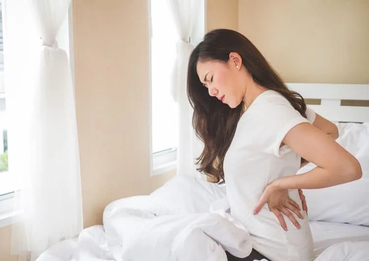 Woman easing lower-back tension, remedial context